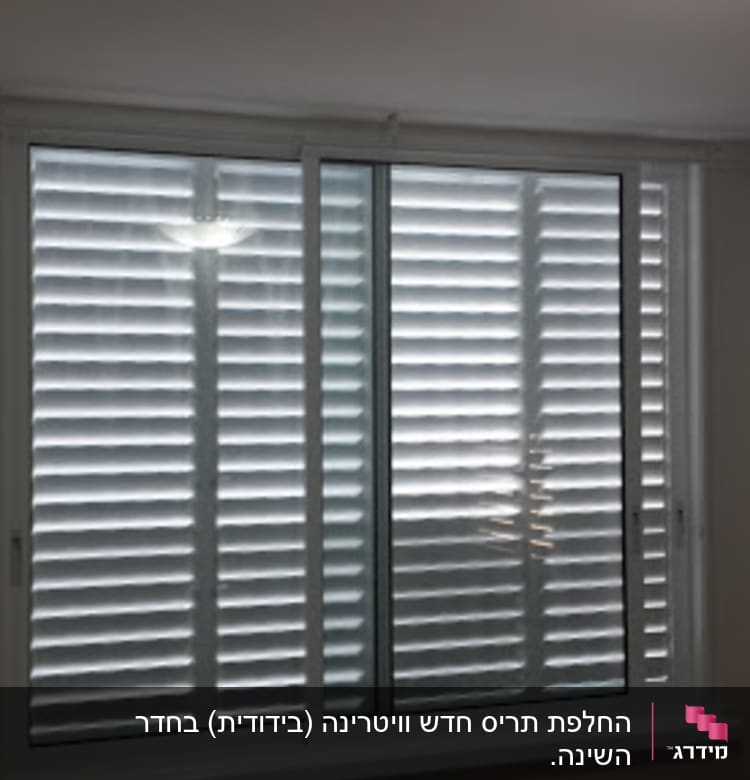 תריסים לבנים סגורים על חלון זכוכית גדול